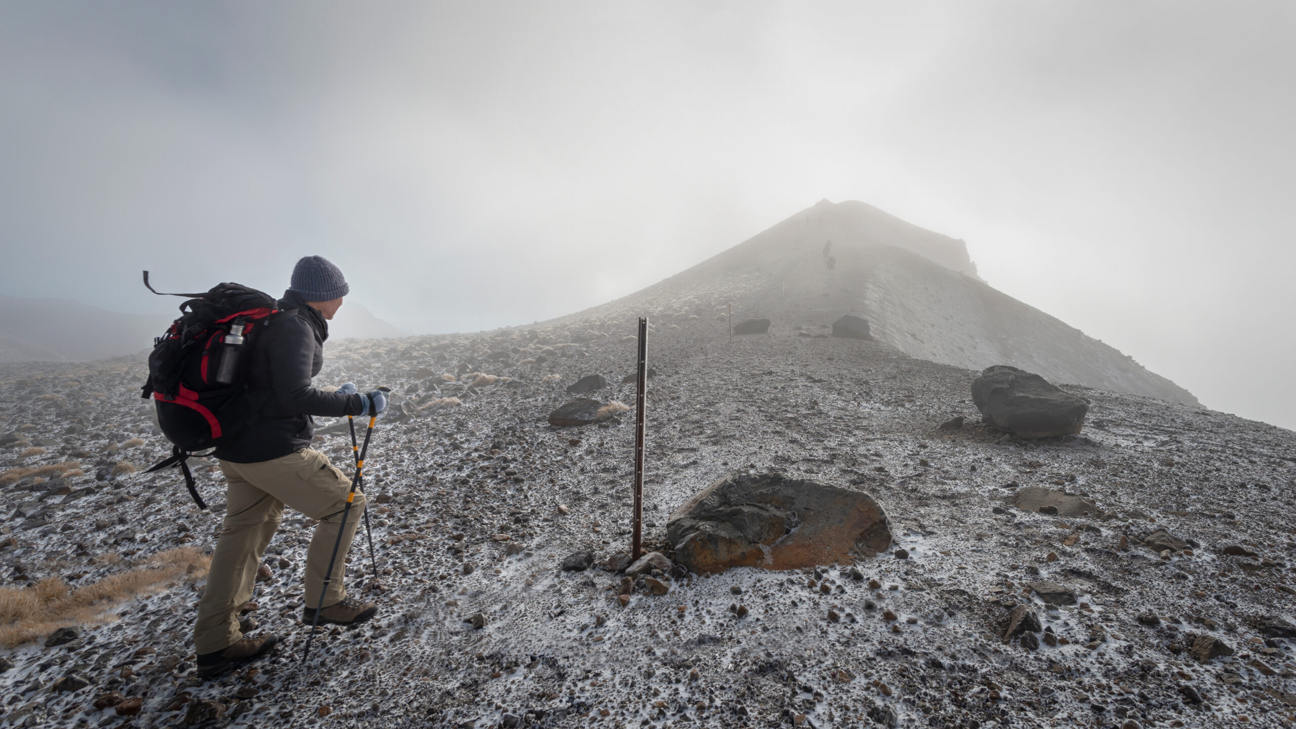 Hiking The Steep Scree Terrain To The Red Crater Summit With Strong Southerly Wind On Tongariro Alpine Crossing. New Zealand.